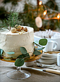 Christmas cake with twigs and golden baubles on a glass cake stand