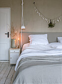 Bed with linen bed linen and bedside table in minimalist bedroom