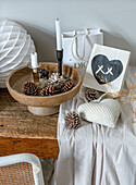 Wooden bowl with pine cones and candles on wooden table