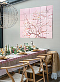 Set dining table with Scandinavian wooden chairs and mural with cherry blossom motif