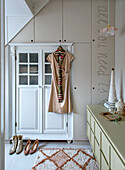 Bedroom with built-in wardrobe, patterned carpet and sideboard, dress hangs on white wardrobe