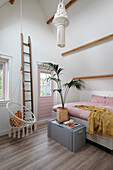 Bedroom under the roof with hanging chair and wooden ladder