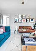 Living room with retro leather sofa, blue couch and picture wall