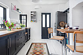 Kitchen with black cabinets, wooden counter and patterned carpet runner