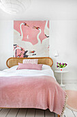 Bedroom with rattan bed, pink wallpaper with heron print and bouquet of tulips