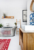 Bathroom with metal bathtub, white brick wall and wooden furniture