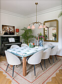 Dining room with table, upholstered chairs, retro lamp, mirror and piano