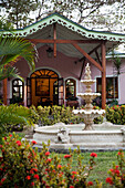 Fountain in the garden in front of a pink house