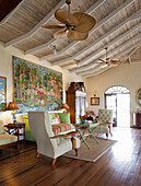 Living room with wooden beamed ceiling, tapestry and striped upholstered armchairs