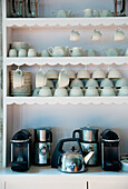 Shelves with white porcelain and coffee machines in the kitchen