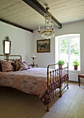 Bedroom with brass bed, crystal chandelier and wooden floorboards