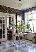 Antique, round table with flower arrangement in a classic hallway with checkered floor