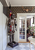 Knight's armour in the hallway with patterned wallpaper and antlers on the wall