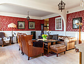 Living room with leather armchairs, Chesterfield sofa and red wallpaper with floral pattern