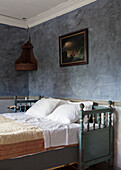 Bed with antique wooden frame in blue-painted bedroom