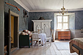 Rustic bedroom with antique white wardrobe and wooden floorboards