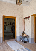 Rustic entrance area with wooden stool and key rack on the wall