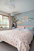 Bedroom with pastel-coloured bed linen and light blue wood panelling