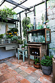 Glass-roofed greenhouse with various plants and antique furniture