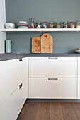 Modern white kitchen with open shelves, storage jars and wooden chopping boards