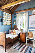 Children's room with antique wooden bed, blue-painted walls and shelf with porcelain plates