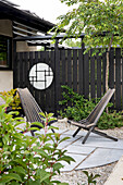 Modern seating area in the garden with black wooden chairs and Japanese-inspired privacy screen