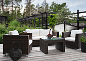 Garden lounge with polyrattan furniture and wooden deck in a green setting