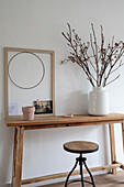 Wooden table with stool, picture frame and vase with twigs