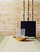 Bamboo in a dark vase in front of brown-beige wallpaper
