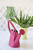 Pink watering can bag and tulips in a yellow vase