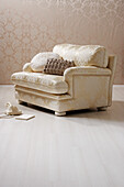 Upholstered armchair with patterned fabric and decorative pillows on a light-colored wooden floor
