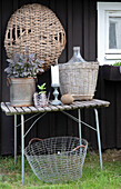 Rustic garden table with basket decoration and candlestick in front of house wall