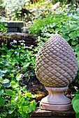 Stone garden statue surrounded by flowering ground cover