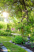 Romantic garden with trellis, flowering shrubs and bench