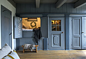 Traditional alcove bed with blue wood panelling and rustic doors