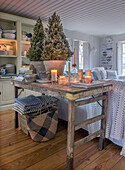 Rustic wooden table with candles, books and fir trees in the living room