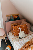 Children's room with sloping roof, cosy cushions and cuddly toy on bed