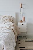 Bright bedroom with crocheted bedspread, rug and bedside table with lamp