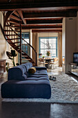 Open-plan living area with blue sofa landscape and wooden spiral staircase