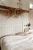 White metal bed with dried flower decoration and bedside table in the bedroom