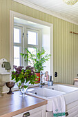 Country kitchen with white sink and green wood paneling