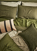 Bed with cushions and blankets in shades of green