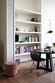 Living area with modern bookshelf and black table on herringbone parquet flooring