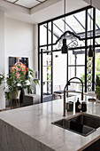 Light-colored kitchen with marble worktop and large windows made of a glass and steel construction