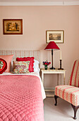 Schlafzimmer mit rosa Wand und rot gemusterten Textilien
