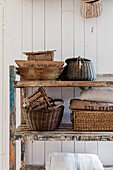 Old wooden shelf with woven baskets in front of white wood paneling