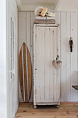 Cabinet in shabby chic look with heart pendant, surfboard next to it