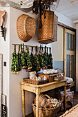 Dried bouquets on wall above antique wooden table and wicker baskets