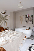 Bedroom with freestanding bathtub and macramé on the wall