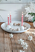 Advent wreath made of wooden beads and red and white striped candles on a wooden table